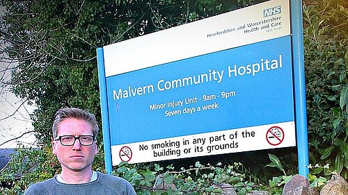 Dan Boatright-PPC looking angry next to Malvern Community Hospital Sign